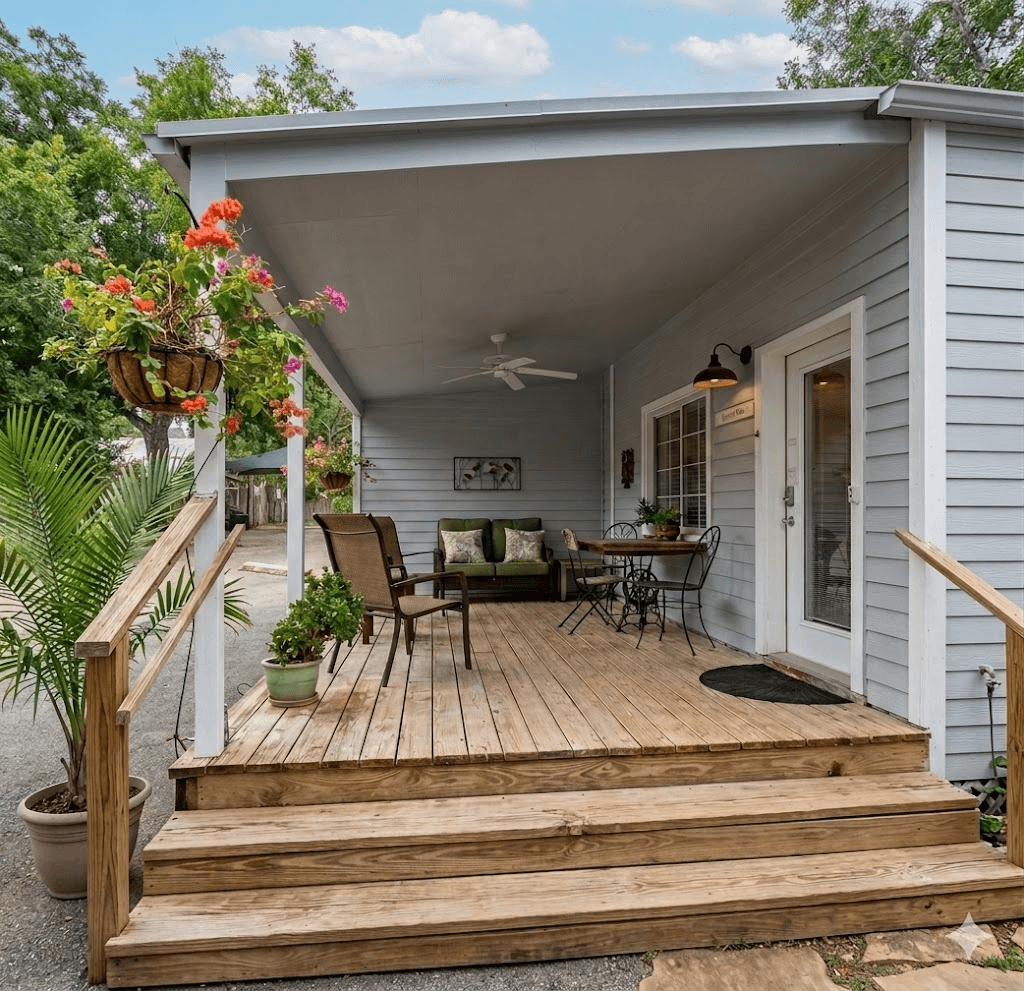 Cypress cottage covered patio with ceiling fan, green sofa, rocking chairs, and colorful hanging flower baskets