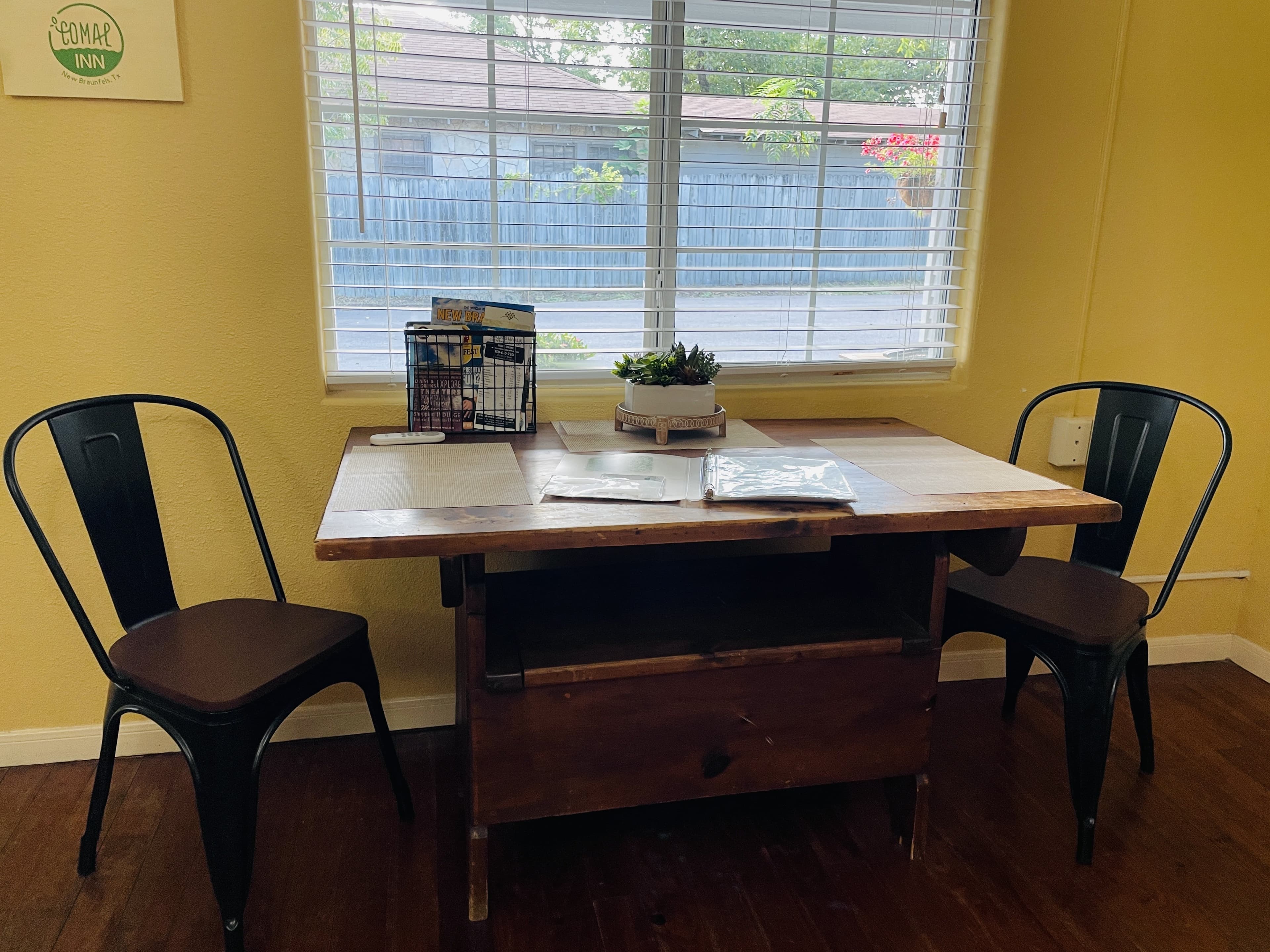 Wood dining table with two chairs by a window in the Cypress Room, used as a workspace