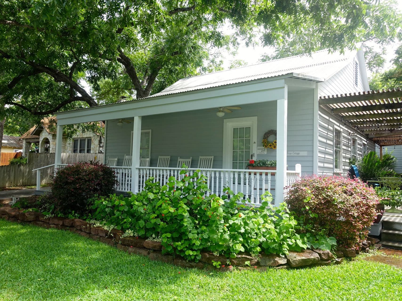Texas Cottage private vacation rental at Comal Inn New Braunfels TX gray-blue cottage with covered porch and lush landscaping