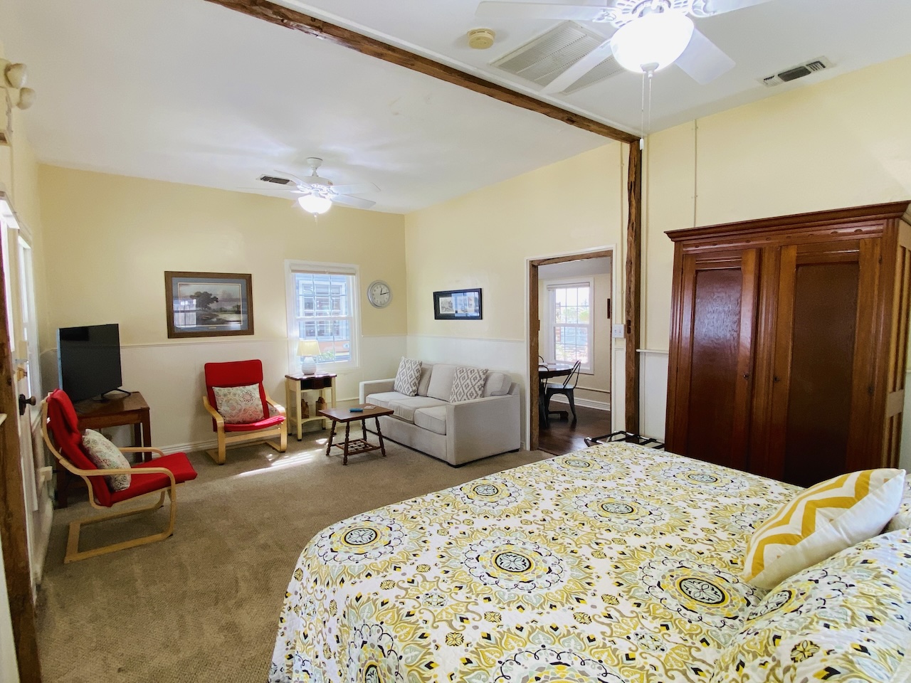 View from the king bed in the living area toward the sitting area with couch, chairs, and TV in the New Braunfels Cottage